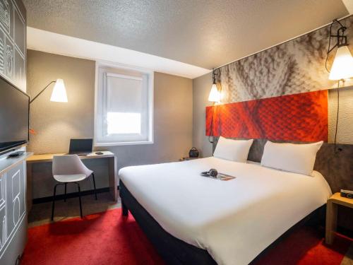Habitación de hotel con cama blanca grande y escritorio. en ibis Paris porte de Bercy, en Charenton-le-Pont