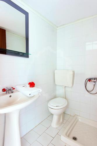 a white bathroom with a toilet and a sink at Zeus Guesthouse in Panayia