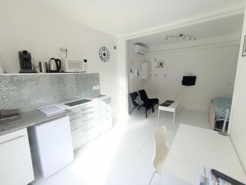 - une cuisine blanche avec un comptoir et une table dans l'établissement Nice House Rent, à Saint-Laurent-du-Var