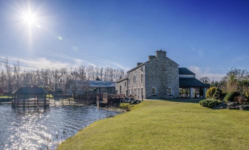 a large stone building next to a body of water at Borwick Lakes Holiday Caravan (Partial Lake View) in Borwick