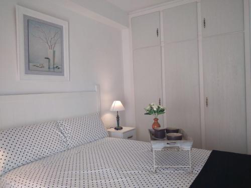 a white bedroom with a white bed and a table at Benalmadena appartament in Benalmádena