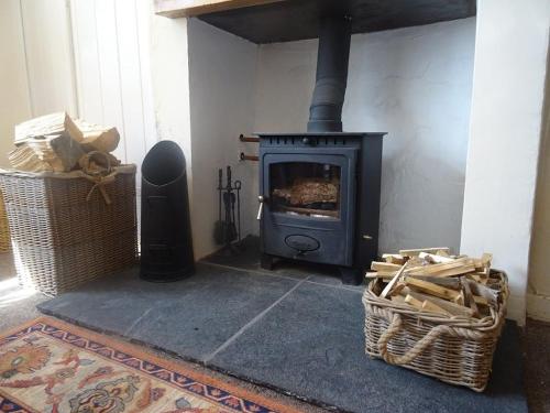 a fireplace with a stove in a room at Shelduck Cottage in Mainsriddle