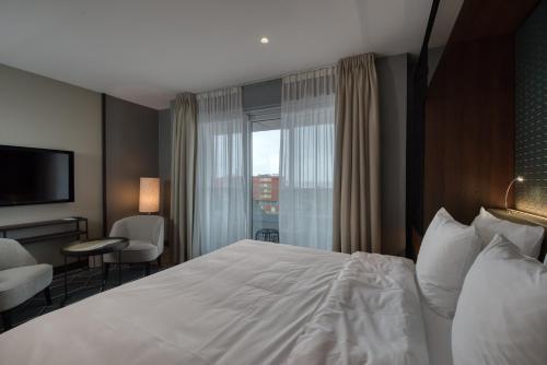 a hotel room with a white bed and a window at Hotel de Schelde in Cadzand-Bad