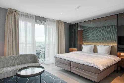 a bedroom with a large bed and a couch at Hotel de Schelde in Cadzand-Bad