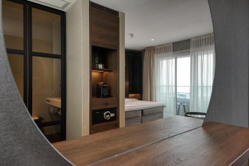 a room with a mirror and a bedroom with a bed at Hotel de Schelde in Cadzand-Bad