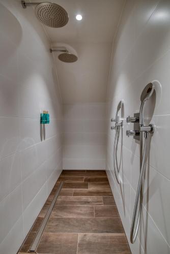 a shower room with white walls and tile floors at Hotel de Schelde in Cadzand-Bad