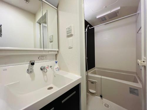 Un baño blanco con lavabo y ducha. en Nishishinjuku 902, en Tokio