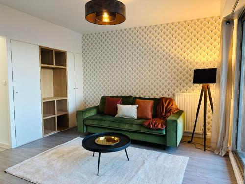uma sala de estar com um sofá verde e uma mesa em Charme, balcon, parking, piscine, tramway, Netflix em Mérignac
