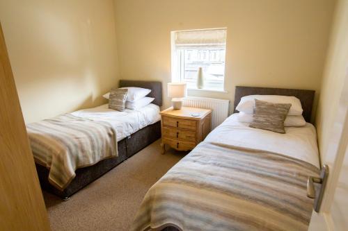 two twin beds in a room with a window at Mulberry Cottage - Cosy 3 Bed Cottage near Lytham Windmill in Lytham St Annes