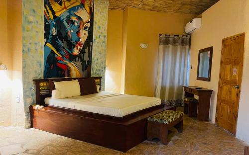 a bedroom with a bed with a painting on the wall at Bamboo Village Resort in Kololi