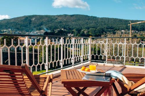 a balcony with two chairs and a table with oranges on it at Just Like Home - Casa do Rosmaninho in Caminha