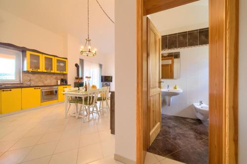 a kitchen with yellow cabinets and a table with a sink at Apartment TOP in Kornić