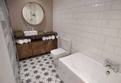 bagno con servizi igienici, lavandino e specchio di Rame Barton Guest House and Pottery a Cawsand
