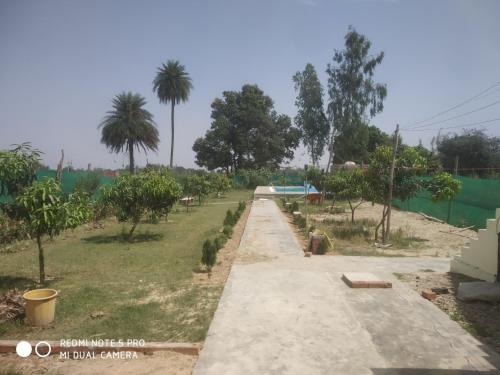 Braj Waterpark & Resort في Kannauj: طريق في ميدان فيه اشجار وسياج