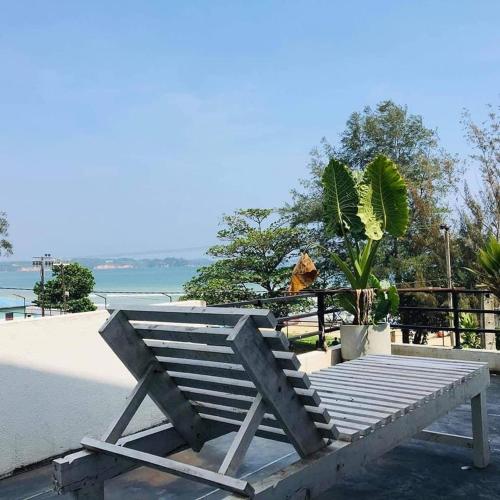 a wooden bench sitting on the beach near the water at Ceylon Surf Guest and Restaurant in Weligama