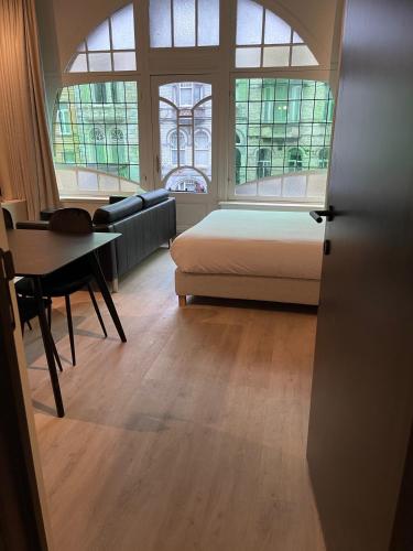 a bedroom with a bed and a table and windows at 3 Bedroom Art-Nouveau Apartment with Free Parking in Ghent