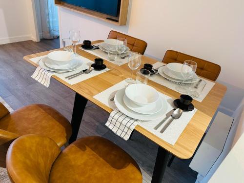 een houten tafel met borden en wijnglazen erop bij Charme, balcon, parking, piscine, tramway, Netflix in Mérignac