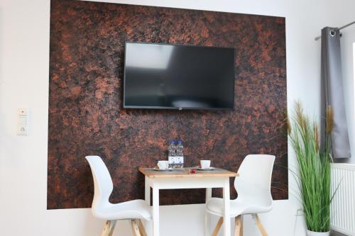 een tafel met stoelen en een tv aan de muur bij Apartments Morsum in Thedinghausen