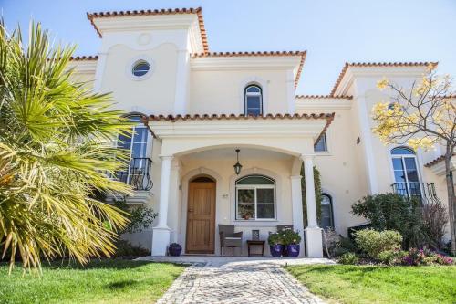 a white house with a door and a lawn at Moradia Geminada com 2 Quartos Quinta do Lago in Quinta do Lago