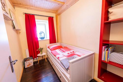a small room with a bed and red curtains at Pension zur Postmeile in Bad Belzig