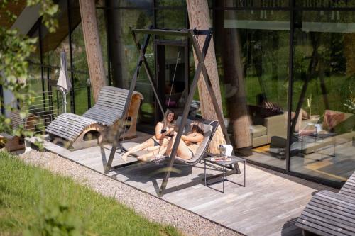 two people are sitting in hammocks on a patio at Moseralm Dolomiti Spa Resort in Nova Levante