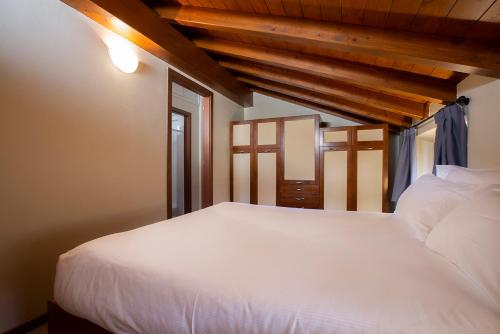 a white bed in a room with wooden ceilings at Antico Pozzo Apartment in Bellagio
