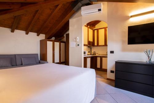 a bedroom with a large white bed and a kitchen at Antico Pozzo Apartment in Bellagio