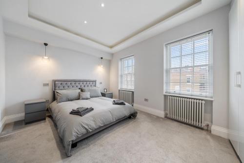 a white bedroom with a bed and two windows at Modern 4 Bedroom Townhouse with Cinema Room in the heart of London SE1 in London