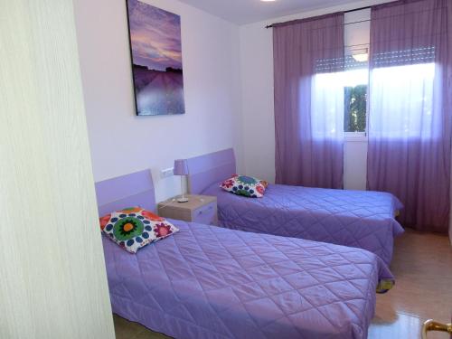 カンブリルスにあるMiramar Serveis- Port Marino Vilafortunyのベッド2台、紫色のカーテン付きの窓が備わる客室です。