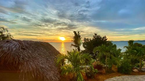 a sunset over the ocean with a straw hut at VERONIKA Resort Nosy Komba in Nosy Komba