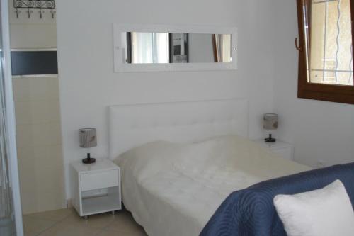 une chambre blanche avec un lit et un miroir dans l'établissement Naturiste Cap d'Agde Villa Port Vénus 49, au Cap d'Agde