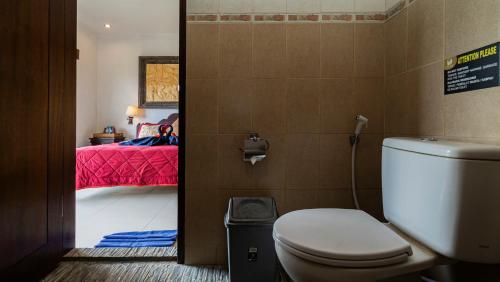 un bagno con servizi igienici e una camera con letto di Kun - Kun Guest House Ubud ad Ubud