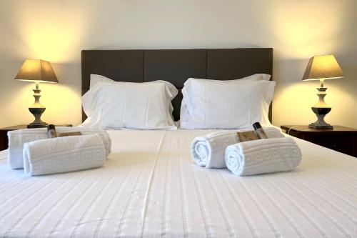 a large bed with white pillows and two lamps at Areias da Rocha by amcf in Portimão