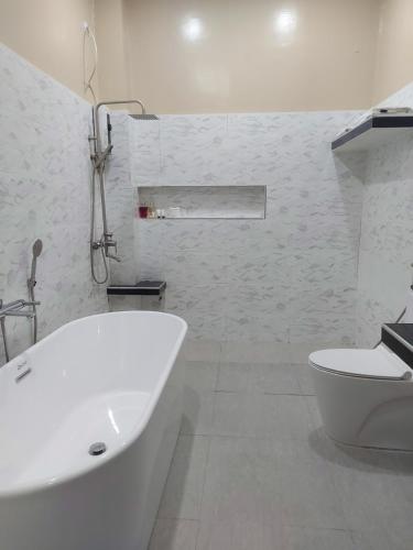 a white bathroom with a tub and a toilet at B&S Orchids suites hotel in Dipolog