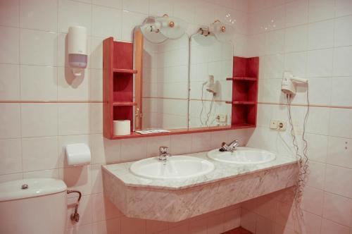 a bathroom with two sinks and a mirror and a toilet at Hotel El Gamo in Tragacete