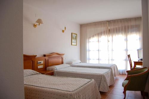 a hotel room with two beds and a window at Hotel El Gamo in Tragacete