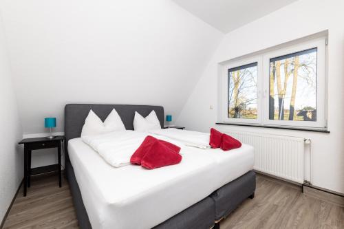 a large white bed with two red pillows on it at Hotel Ehlers in Schneverdingen