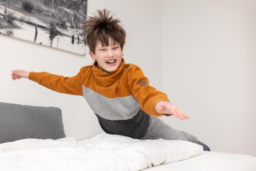 a young boy jumping on top of a bed at Hotel Ehlers in Schneverdingen
