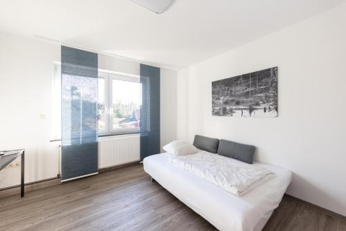 a white bedroom with a bed and a window at Hotel Ehlers in Schneverdingen