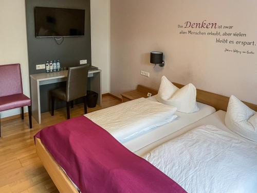 a hotel room with two beds and a desk at Torstuben in Tettnang