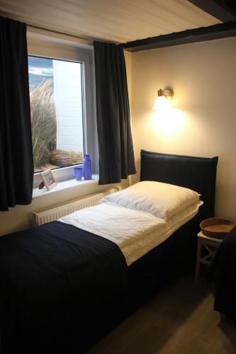 Schlafzimmer mit einem großen Bett und einem Fenster in der Unterkunft Reetdach Friesenhof Süderende in Westerland