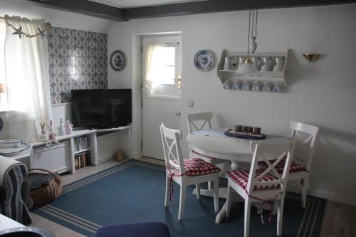 ein Wohnzimmer mit einem Tisch, Stühlen und einem TV in der Unterkunft Reetdach Friesenhof Süderende in Westerland