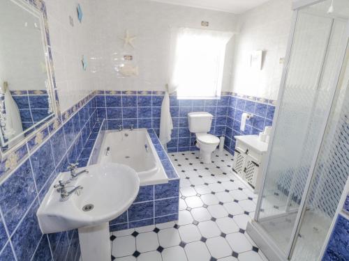 baño azul y blanco con bañera y lavamanos en Pine View, Longford, en Longford