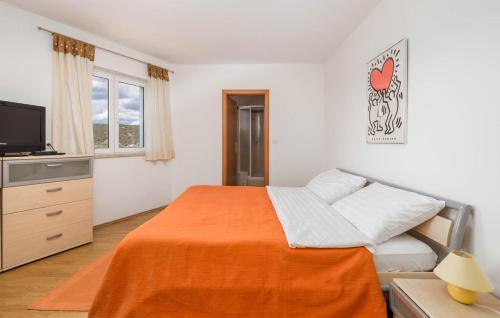 a bedroom with a bed with an orange blanket at Apartments Dedić in Supetarska Draga