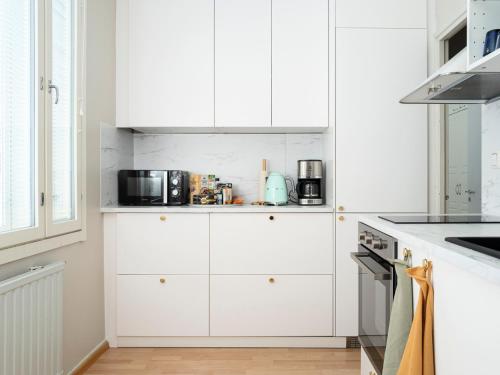 uma cozinha branca com armários e electrodomésticos brancos em City Home Hämeenpuisto - HighSpeed 5G WIFI em Tampere