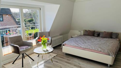 una camera da letto con un letto e un tavolo con un vaso di fiori di Ferienwohnung-Weidenstieg-OG a Wenningstedt