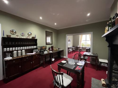 un comedor con mesas y sillas y una habitación con ventana en Pendrin Guest House en Tintagel