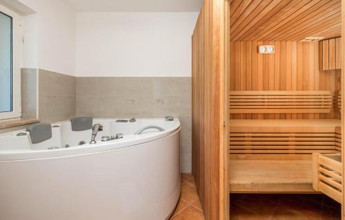 a bath tub in a bathroom with a wooden wall at Apartments Dedić in Supetarska Draga