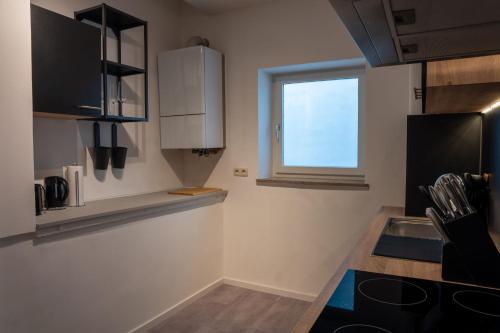 eine Küche mit weißen Schränken und einem Fenster in der Unterkunft Altstadtjuwel Liboria in Augsburg