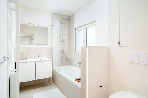 een witte badkamer met een bad en een douche bij CAPRINO Guesthouse in Knokke-Heist